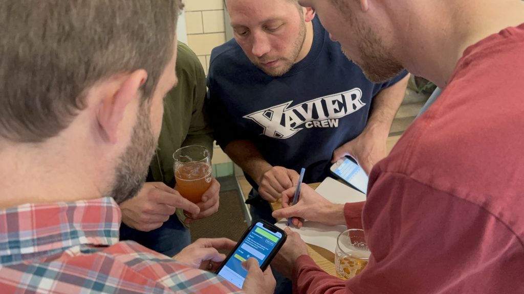 High Grain Brewing Team looking at phone over shoulder