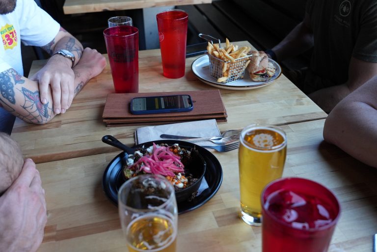 Friends eating sandwiches and fries with craft beer at Lost Grove Brewing in Boise Idaho
